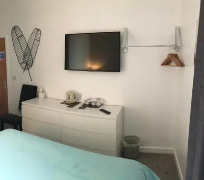 a bedroom with a dresser with a tv on the wall at Four Seasons Guest House in Blackpool