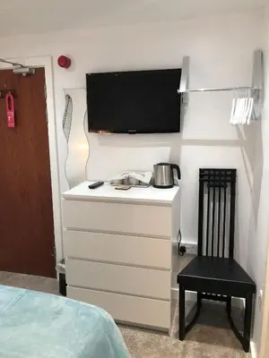a bedroom with a dresser with a tv and a chair at Four Seasons Guest House in Blackpool