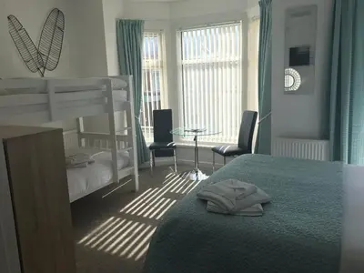 a bedroom with a bunk bed and a table and chairs at Four Seasons Guest House in Blackpool