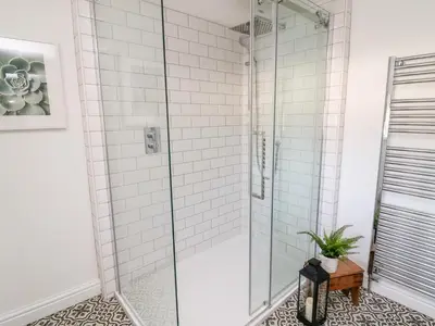 a shower in a bathroom with white tiles at 3 Poole End in Clitheroe