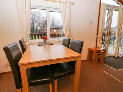 a dining room table with black chairs and a window at The Cedars in Carnforth