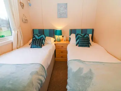 two twin beds in a room with a dresser at The Cedars in Carnforth