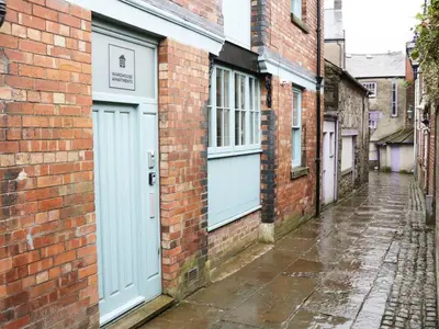 an alley with blue doors on a brick building at Warehouse Apartments 1Bed Sleeps 2 Pets Welcome in Ulverston
