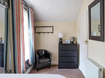 a bedroom with a chair and a dresser and a mirror at The Shores Hotel, Central Blackpool in Blackpool