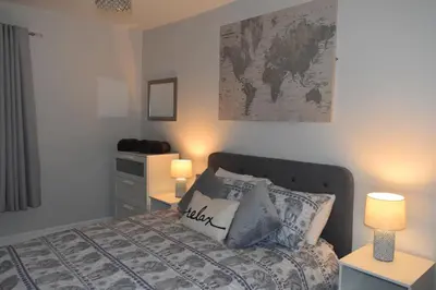 a bedroom with a bed with two lamps and a map on the wall at Pleasure Beach House in Blackpool