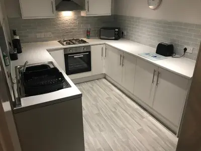 a kitchen with white cabinets and a stove top oven at Pleasure Beach House in Blackpool
