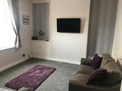 a living room with a couch and a tv on a wall at Pleasure Beach House in Blackpool
