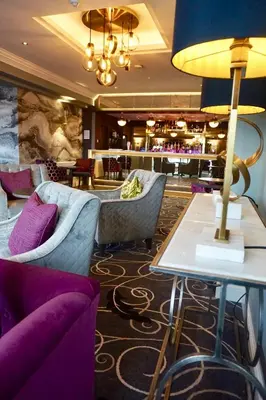a hotel lobby with purple chairs and a table at Hotel Sheraton in Blackpool