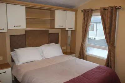 a bedroom with a large bed with a window at Port Haverigg Holiday Village in Millom