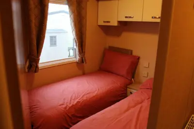 a small room with two beds and a window at Port Haverigg Holiday Village in Millom
