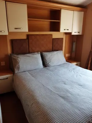 a bedroom with a bed with white sheets and white cabinets at Port Haverigg Holiday Village in Millom