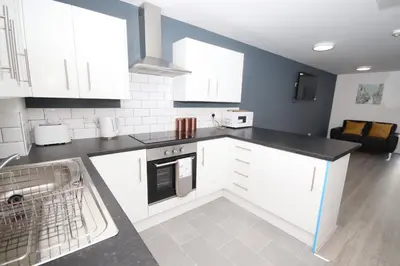 a kitchen with white cabinets and a black counter top at Fox Street Delight in Liverpool