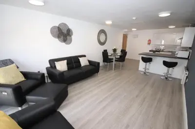 a living room with a black couch and a kitchen at Fox Street Delight in Liverpool