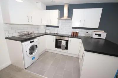 a kitchen with white cabinets and a washing machine at Fox Street Delight in Liverpool