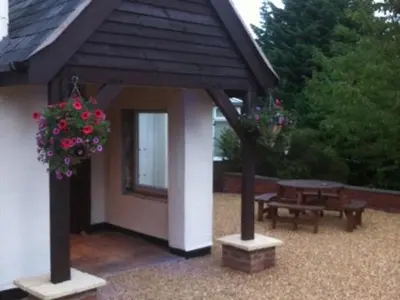 a gazebo with a table and a bench and flowers at The Liver View in Birkenhead