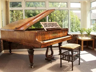 a piano in a room with a chair and windows at The Liver View in Birkenhead