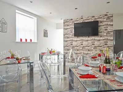 a dining room with a table with chairs and a tv at 88 Anfield Road in Liverpool
