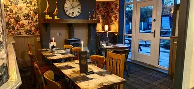 a restaurant with tables and chairs and a clock on the wall at The Strawbury Duck Inn in Darwen