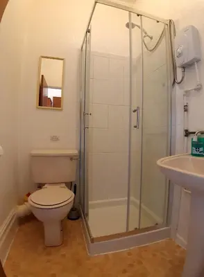 a bathroom with a shower and a toilet and a sink at Rosemede Holiday Flats in Blackpool