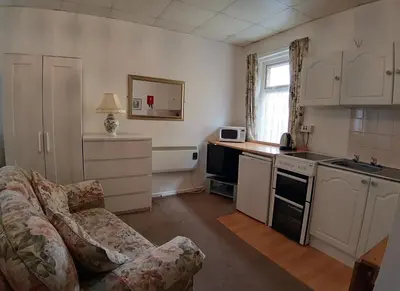 a living room with a couch and a kitchen at Rosemede Holiday Flats in Blackpool