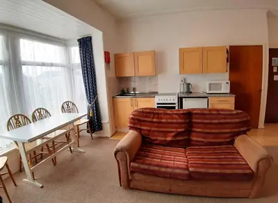 a living room with a couch and a table and a kitchen at Rosemede Holiday Flats in Blackpool