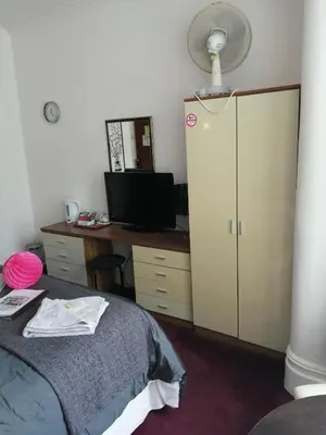 a bedroom with a bed and a desk with a fan at The Garnett in Blackpool