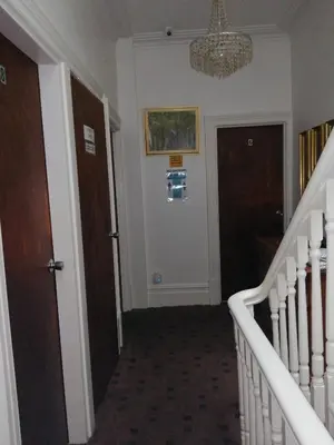a hallway with stairs and a chandelier at The Garnett in Blackpool