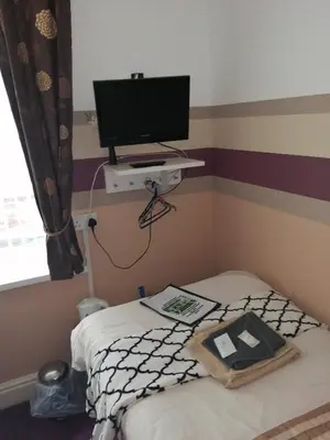 a bedroom with a bed with a television on a shelf at The Garnett in Blackpool