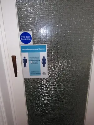 a bathroom stall with signs on the door at The Garnett in Blackpool