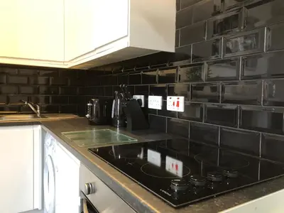 a kitchen with a black tiled wall at Fishergate ApartHotel 2 - City Centre Location in Preston