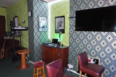 a living room with a tv and a chair and a stool at The Rowan Hotel in Blackpool