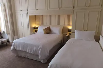 two beds in a hotel room with white sheets at The Rowan Hotel in Blackpool