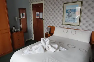 a bedroom with a white bed with towels on it at The Rowan Hotel in Blackpool