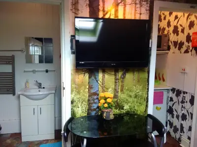 a bathroom with a tv and a table and a sink at K.k's North Station Self catering holiday apartments in Blackpool