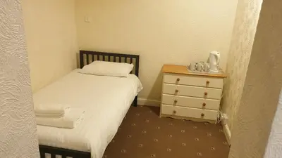 a small bedroom with a bed and a dresser at HOTEL242 in Blackpool