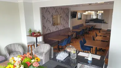 a restaurant with wooden tables and blue chairs at HOTEL242 in Blackpool