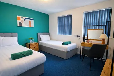 a room with two beds and a desk and a chair at Royal Chambers Liverpool in Liverpool