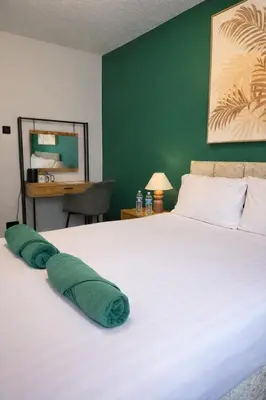a bedroom with a white bed with a green wall at Royal Chambers Liverpool in Liverpool