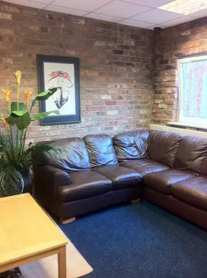 a brown leather couch in a room with a brick wall at Royal Chambers Liverpool in Liverpool