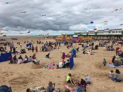 a crowd of people on a beach flying kites at Beach Hideaway in Lytham St Annes