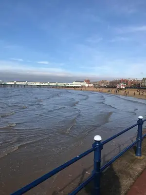 a blue fence on the beach with a train in the background at Beach Hideaway in Lytham St Annes