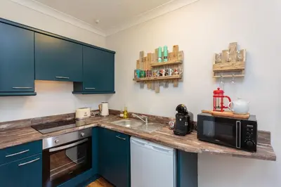 a kitchen with blue cabinets and a counter with a microwave at Beach Hideaway in Lytham St Annes