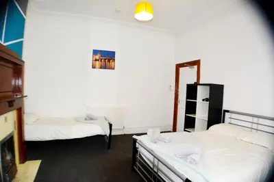a room with two beds with white sheets and a mirror at Old Swan Guest House in Liverpool