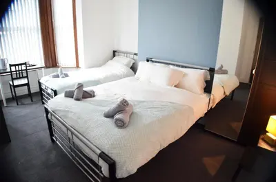 two beds in a room with two pairs of slippers at Old Swan Guest House in Liverpool