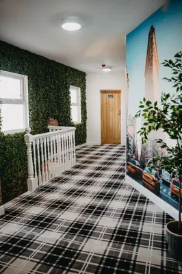 a room with green walls and a hallway with a staircase at Flat Iron Anfield in Liverpool