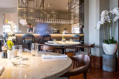 a restaurant with tables and chairs and a man in the background at The Grand Hotel in Lytham St Annes
