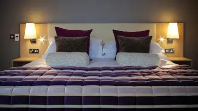 a large bed with purple and white sheets and pillows at The Grand Hotel in Lytham St Annes