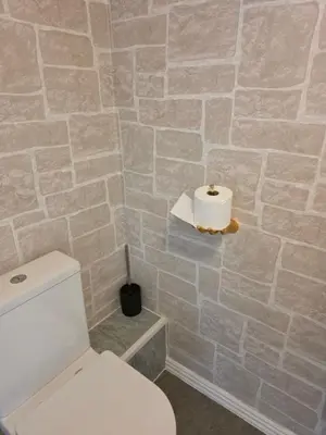 a bathroom with a white toilet and a stone wall at Bluebell Hotel in Blackpool