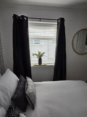 a bedroom with a bed with black curtains and a window at Bluebell Hotel in Blackpool