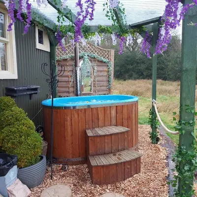 a hot tub in a yard with purple flowers at Little Oakhurst in Clitheroe